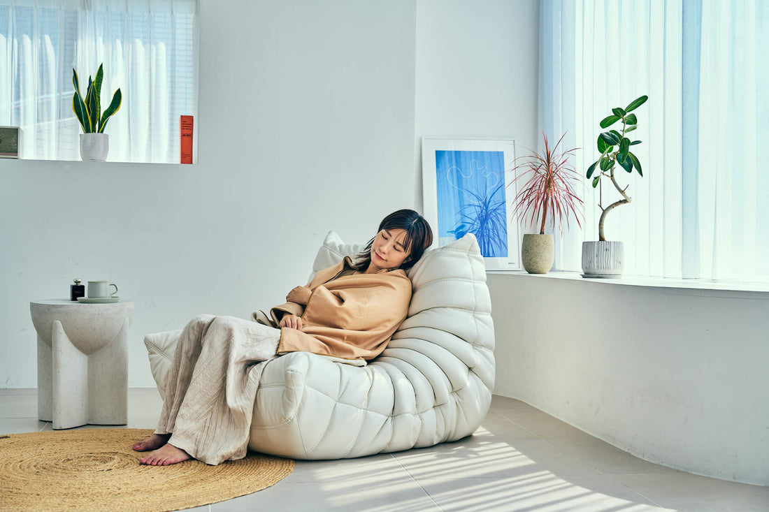 温泉ヒーリングブランケットをひざに掛けて、ソファでくつろぐ女性（SLEEP HEXAGON）