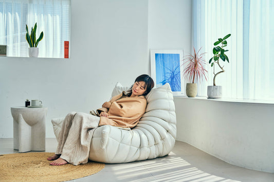 温泉ヒーリングブランケットをひざに掛けて、ソファでくつろぐ女性（SLEEP HEXAGON）